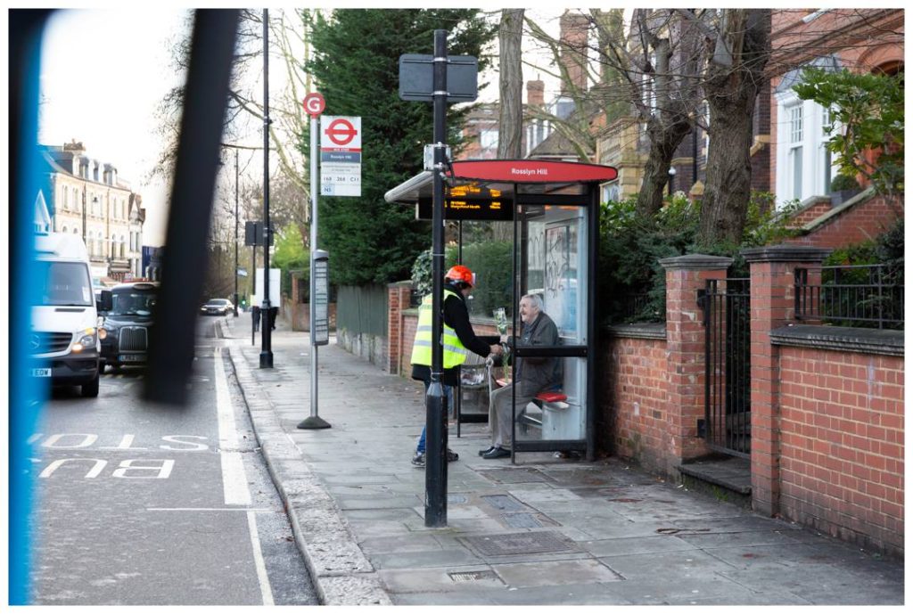 Charity Event photo in London of Volunteer giving man flowers at the bus stop