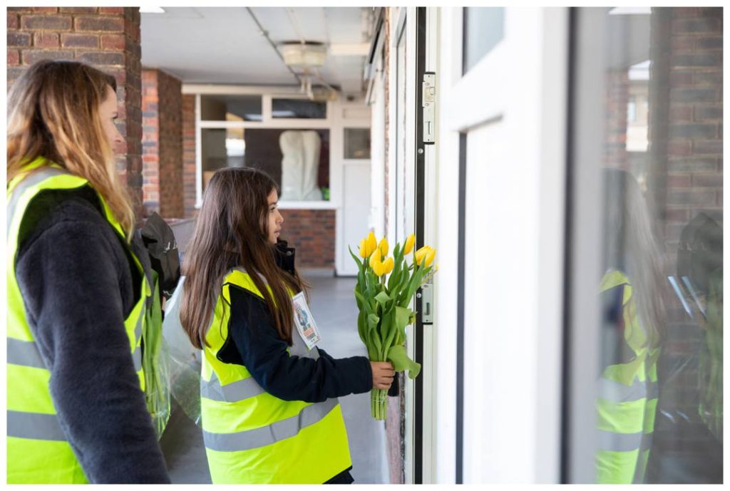 Child giving yellow tulips to elderly residents