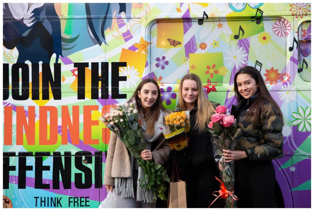 Three young women and their Kindness Offensive flowers