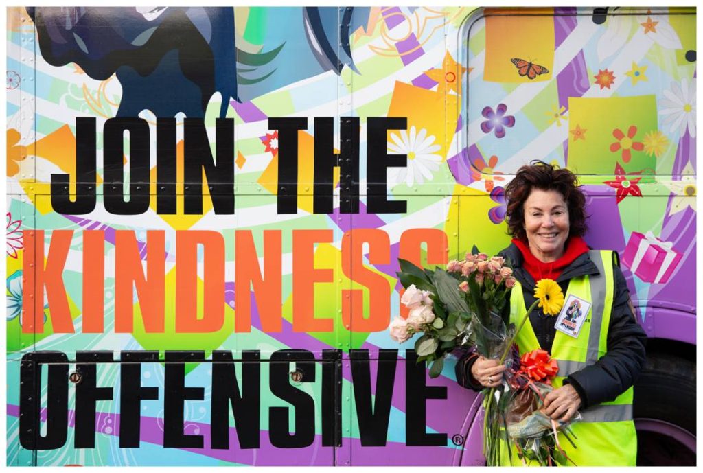 Ruby Wax holding flowers by the Kinder bus
