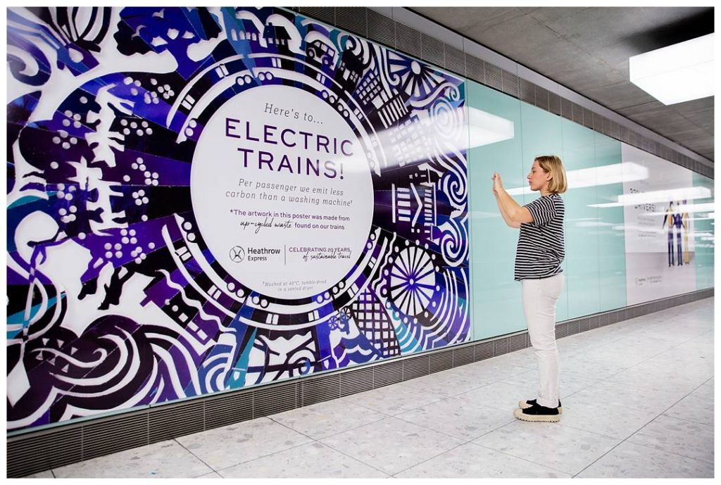 Lady taking a photo of the electric trains poster